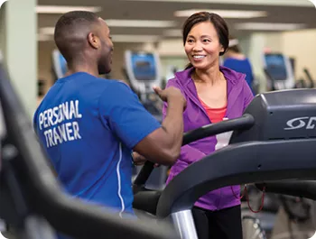 Personal trainer talking to member on a treadmill