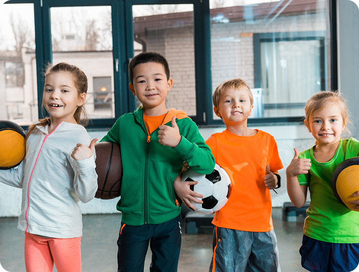 four kids posing with sports balls