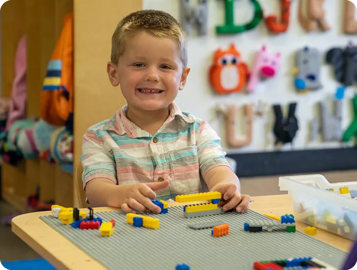 smiling boy playing with legos