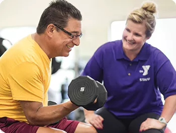 Man and Personal Trainer lift a dumbbell together