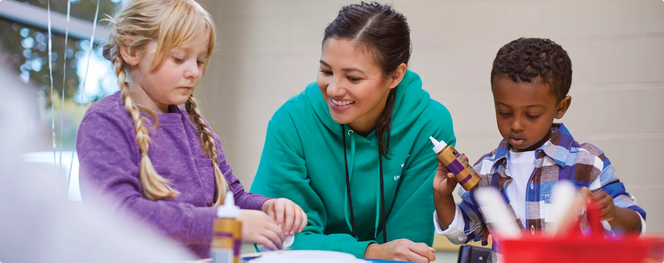 staff member doing crafts with two children