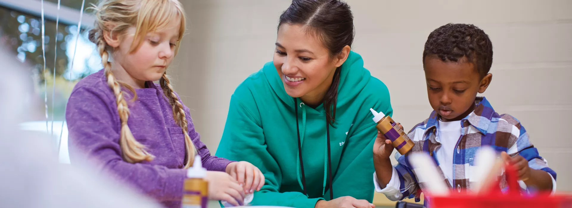 staff member doing crafts with two children